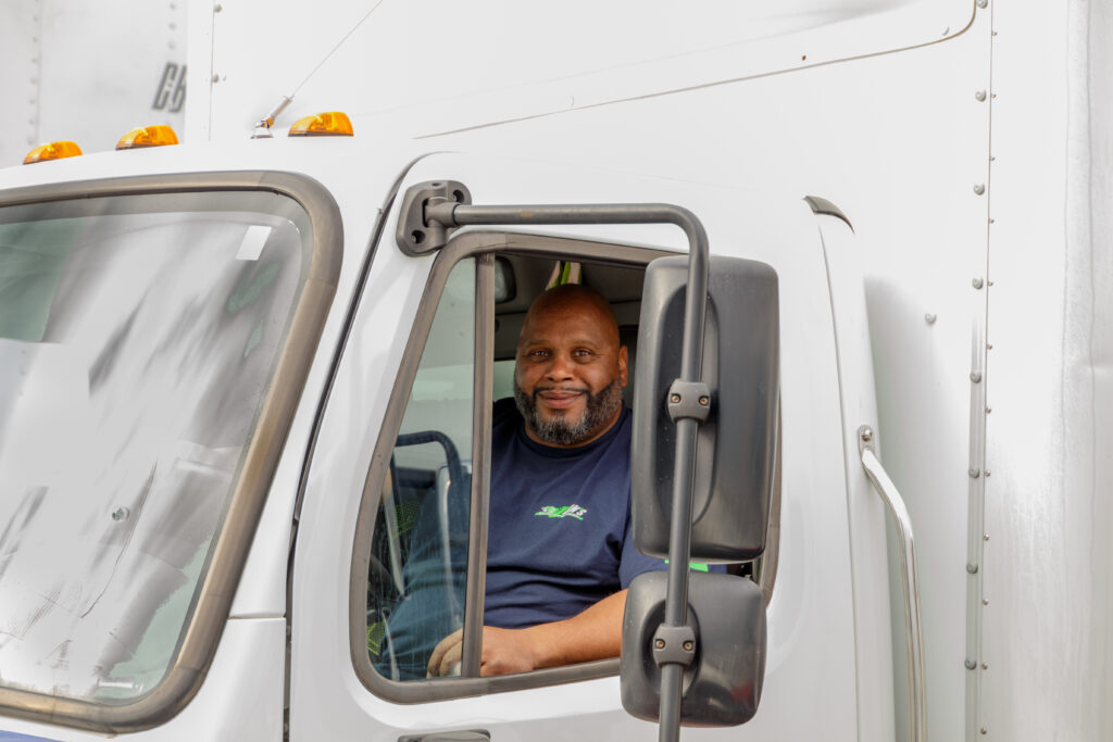 Navigating PNW Summer Road Construction With Local Delivery Trucking Strategies Dan's Delivery worker sitting in his truck smiling