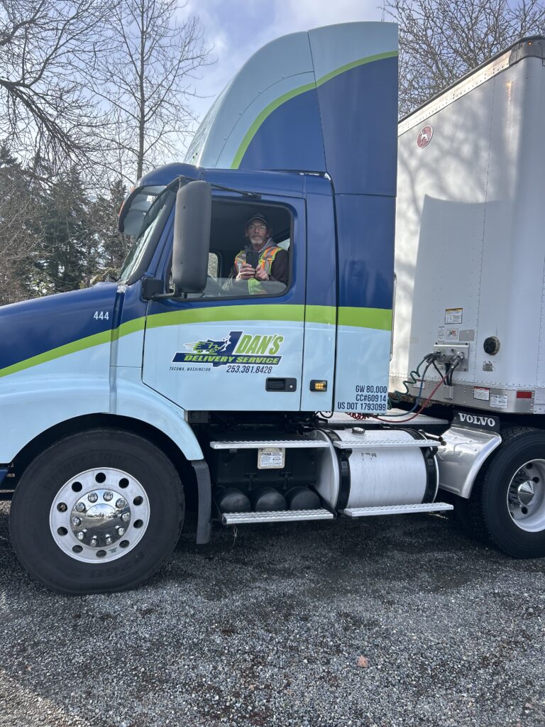 man sitting in a Dan's Delivery semi truck | local delivery trucking