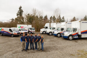 Dan's delivery team standing outside of their fleet of trucks | summer freight transport & shipping